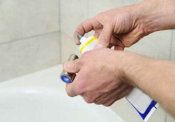 Plumber putting a paste sealant.