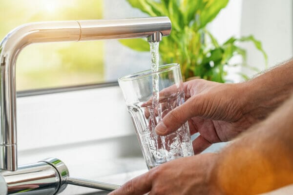 Closeup shot of a man pouring a glass of fresh water from a kitc