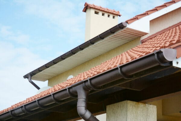 Rain gutters system on new house with chimney, red clay tiled r